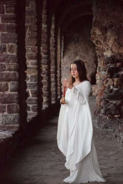 Jeune princesse médiévale vêtue de blanc et protégeant la flamme d'une bougie