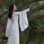 Femme en robe blanche medievale faisant signe d'arrêter avec sont bras tendu paume ouverte