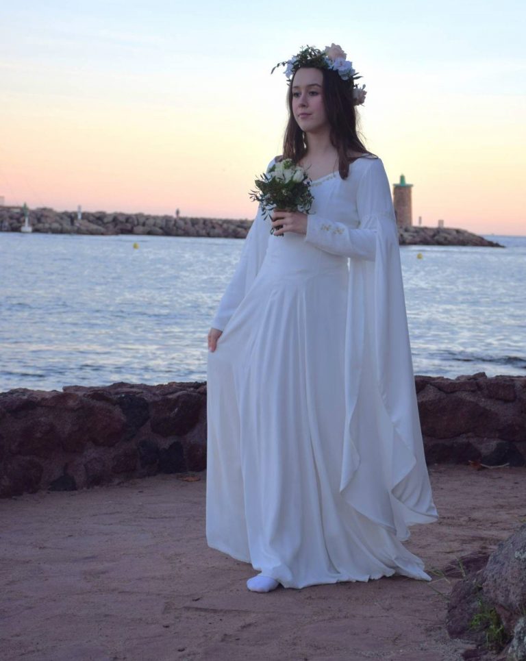 Une mariée en robe blanche romantique fantasy marche au bord de la mer