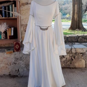 Robe blanche de mariée féérique que un mannequin près d'une étagère remplie de livres