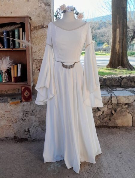 Robe blanche de mariée féérique que un mannequin près d'une étagère remplie de livres