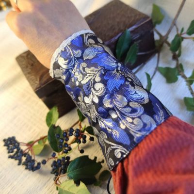 manchons de poignets fantasy avec motif fleur de lys, portés au poignet par une personne, réalisée en très petite série dans un tissu jacquard de qualité. Soyez la reine d’un soir en portant cette ceinture royale.
