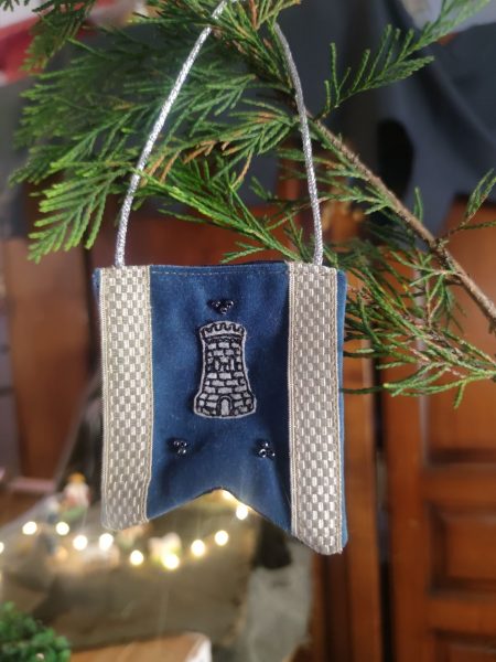 décoration en forme de bannière d'inspiration médiévale fantasy suspendue à une branche de sapin