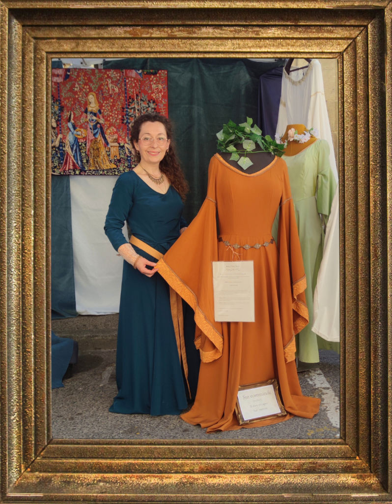 Couturière costumée présentant ses créations sur ds mannequins devant son stand, entouré d'un cadre