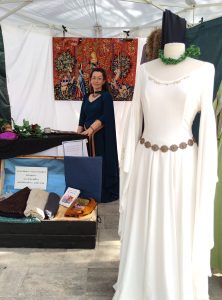 Couturière de costumes fantasy dans on stand à côté d'un mannequin vêtu d'une robe de mariée médiévale